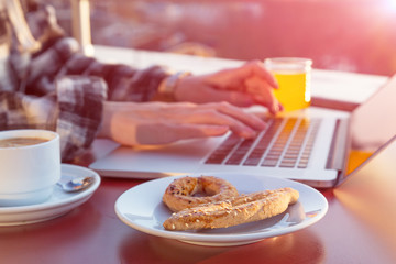 Person sitting at wood desk working on laptop computer drinking coffee