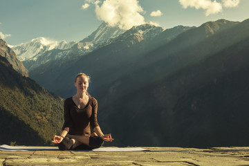 Young Female doing yoga meditation outdoor in beautiful mountains landscape. Exercise for Health, relaxation