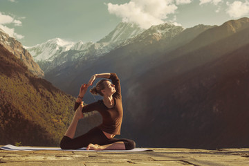 Young woman doing yoga exercise pigeon asana in beautiful mountains