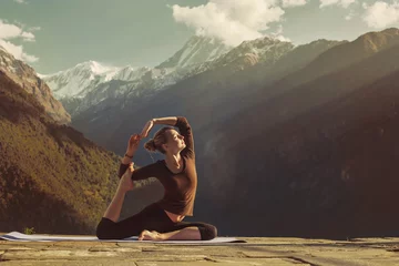 Papier Peint photo Himalaya Jeune femme faisant du yoga exercice pigeon asana dans de belles montagnes