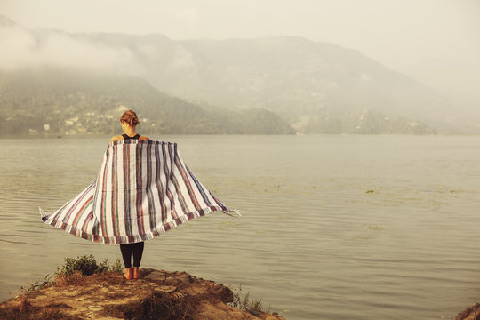 Girl in plaid blanket standing near mountain lake. Calm, melancholy, relax. quiet natural place outdoor, abstract travel