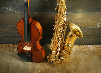 Beautiful golden saxophone with violin on wooden background, close up