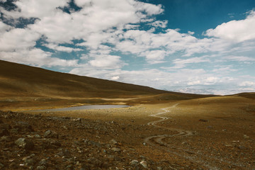 Curve Way Road in mountains landscape with sun spot and clouds