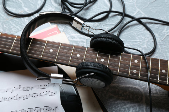 Electric guitar and headphones with music notes on grey background