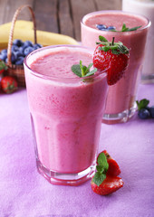 Glasses of fresh cold smoothie with fruit and berries, on the table, close-up