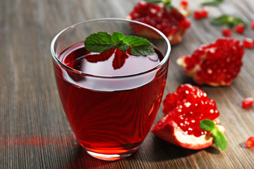 A glass of tasty juice and garnet fruit, on wooden background