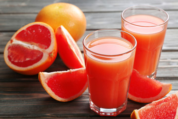 Glass of grapefruit juice and fresh fruits on wooden background
