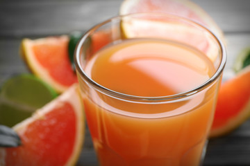 Glass of grapefruit juice and fresh fruits on wooden background