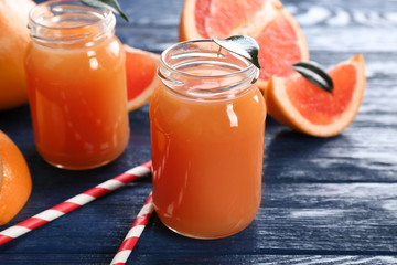 Grapefruit juice in bottles and fresh fruits on dark blue wooden background