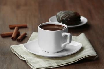 Cup of cacao with biscuits and cinnamon on wooden table