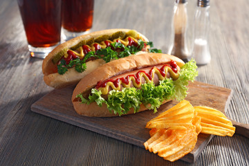 Delicious hot-dog with chips on wooden background