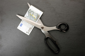 Concept of spending money - scissors cut money on black background
