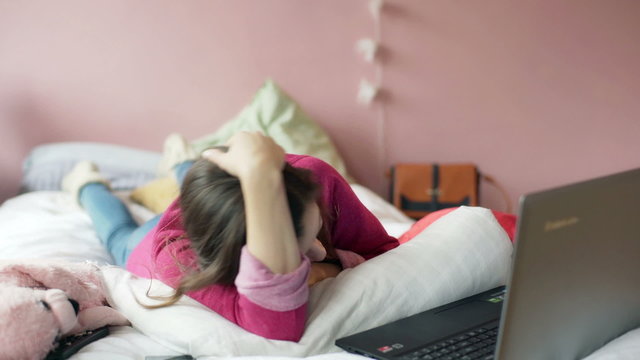 Worried girl having a videocall on laptop and lying on bed
