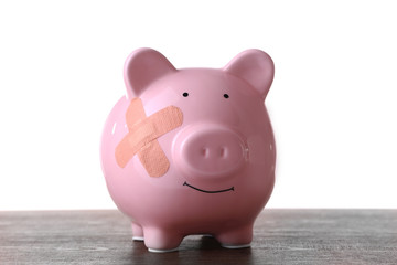 Piggy Bank with adhesive bandage wooden table, on white background