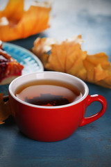 Cup of tea with autumn decor on wooden table.