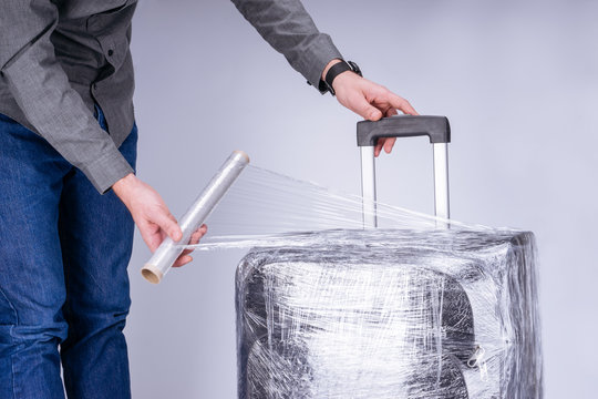 Man wraps suitcase protective film