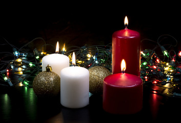 Burning candles on black background with electric garland