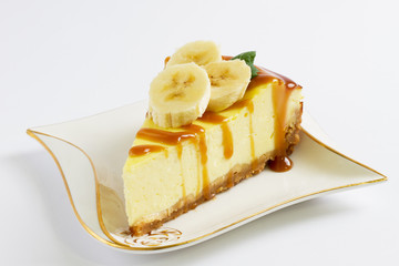 Slice of cheesecake topped with caramel sauce on plate on wooden table, close up