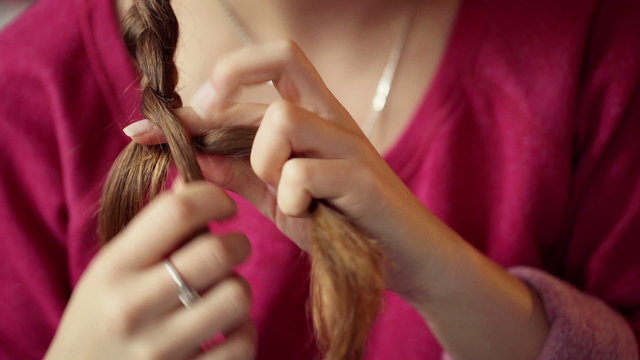 Girl making herself a braid on her hair, steadycam shot
