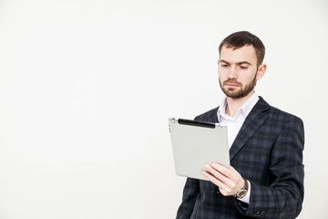 Portrait of a handsome young bearded man wearing a formal black suit holding a tablet