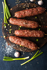 Raw kebabs  with seasoning , onion and garlic on the wooden board top view