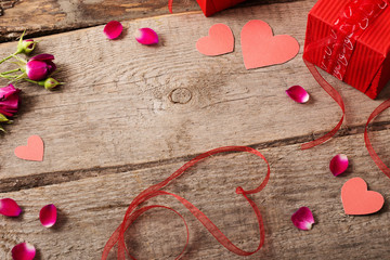 valentine gift box and red heart shapes on wooden board
