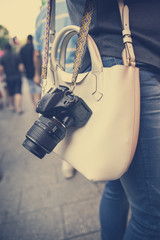 Young woman holding a bag and a digital camera walking on the streets of New York, USA. Young fashion, style, lifestyle, urban and travel concept