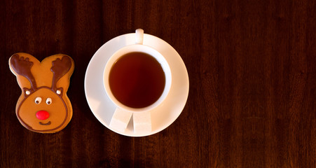 White Cup of tea, a saucer of sugar cubes, painted stick figure reindeer, wooden background