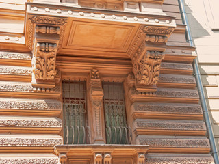Old mansion façade with stucco molding balcony and ornate metal bars before window. Moscow, Russia. 
