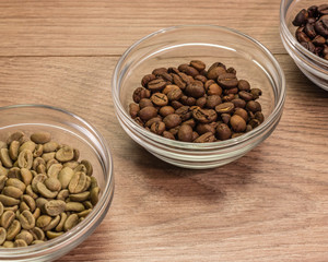 Coffee beans of medium roast in a glass bowl surrounded by green
