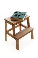 Vintage Book and Glasses are Laying on Wooden Stool