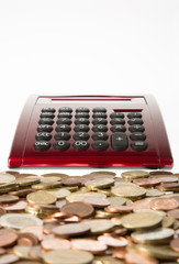 Gemischte Euro-M&uuml;nzen vor einem Rechner auf einem Tisch liegend 