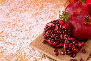 Fresh ripe pomegranates on wooden background and Christmas decoration.