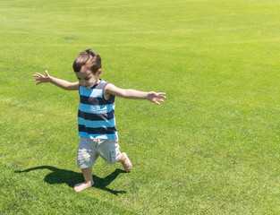 Fototapeta premium Little kid running on green meadow