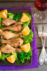 Dish with roasted chicken legs, greens, oranges and wine.