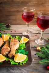 Baked chicken legs on a plate with greens, oranges and cranberries. Christmas decorations