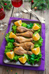 Chicken drumsticks on a plate with salad, orange and cranberries