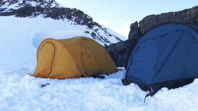 High-altitude camp in a snow mountain. Team of climbers on the high mountain set up the tents. Russia, Altai, South Chui range, Iiktoo peak, altitude 4000 m. May 2015.