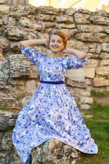 Beautiful blonde girl in blue dress posing against a background