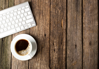 Keyboard, cup of coffee on a wooden background