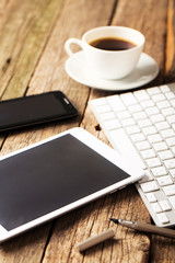 Office concept. Keyboard, tablet pc, and coffee on old wooden ta