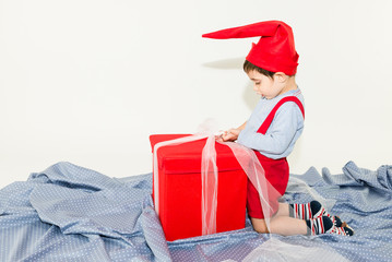 Happy caucasian toddler with funny hat opening a big gift box - isolated on white background