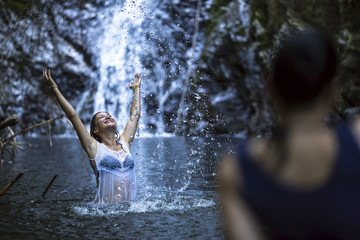 An attractive young woman bathing near the waterfall.