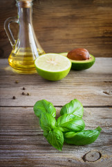 Sprig of basil in the background avocado, lime and olive oil.