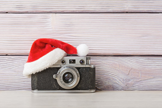 Old camera in santa hat on wooden background