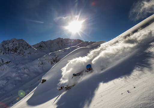 A freeride skier make a turn in powder snow on a sunny day in western Austria