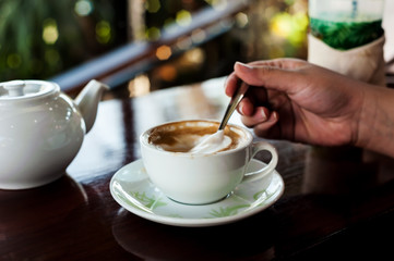 Cup of coffee with hot tea pot on wooden in over dark tone
