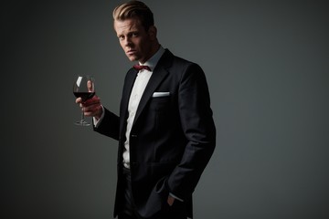 Confident sharp dressed man with glass of wine