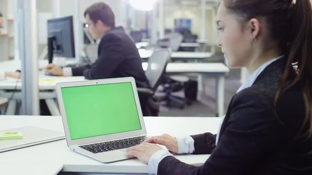 Female Office Worker using Notebook with Green Screen. Great for Mockup usage. Shot on RED Cinema Camera.