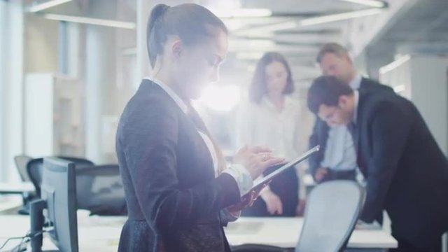 Businesswoman is using Tablet PC in Crowded Office. Shot on RED Cinema Camera